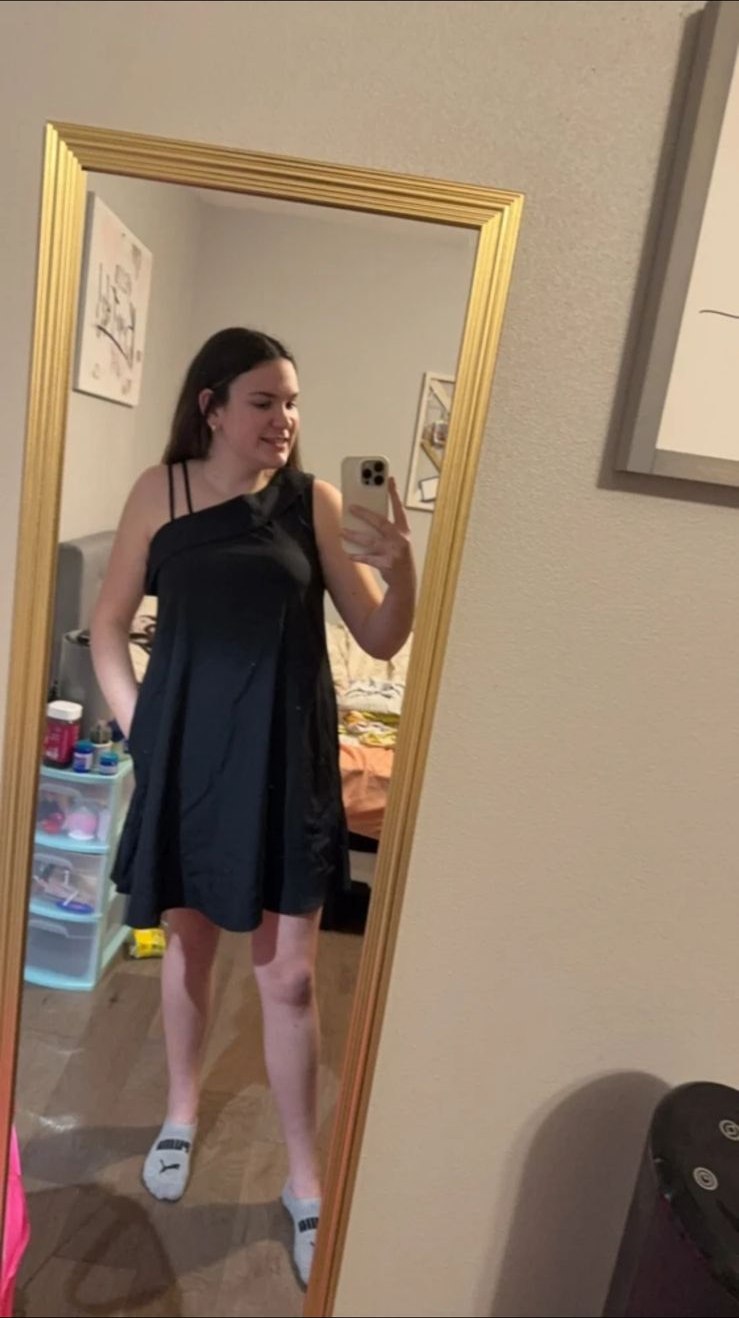 Person in einem locker geschnittenen schwarzen Minikleid